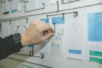 person-working-on-blue-and-white-paper-on-board.jpg person working on blue and white paper on board